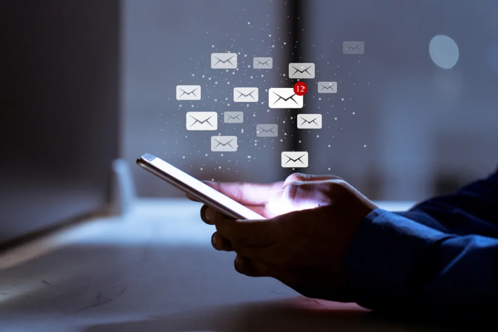 Person checking email on a phone with message icons floating above the screen