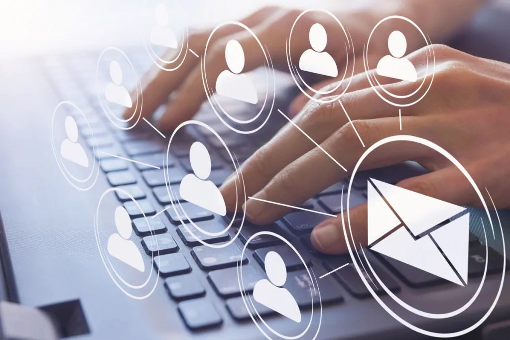 Hands typing on a laptop with email and audience segment icons overlaid