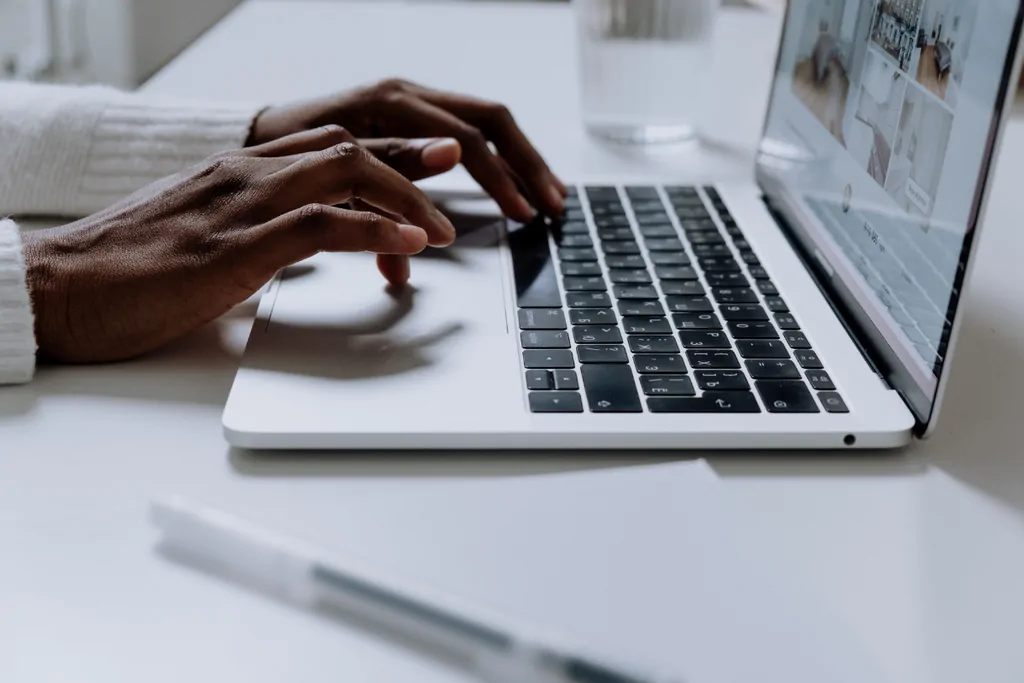 Person typing on a laptop at a white desk